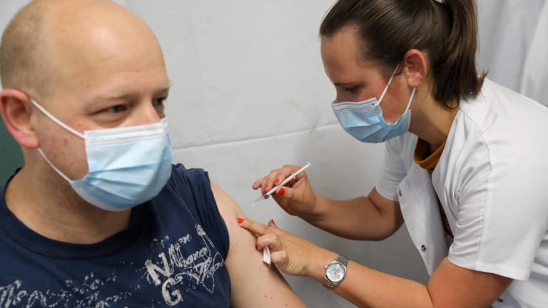 Eine Frau impft einen Mann in Lille (Archivbild). Wissenschaftler halten eine höhere Impfquote für notwendig, um eine vierte Welle zu vermeiden.