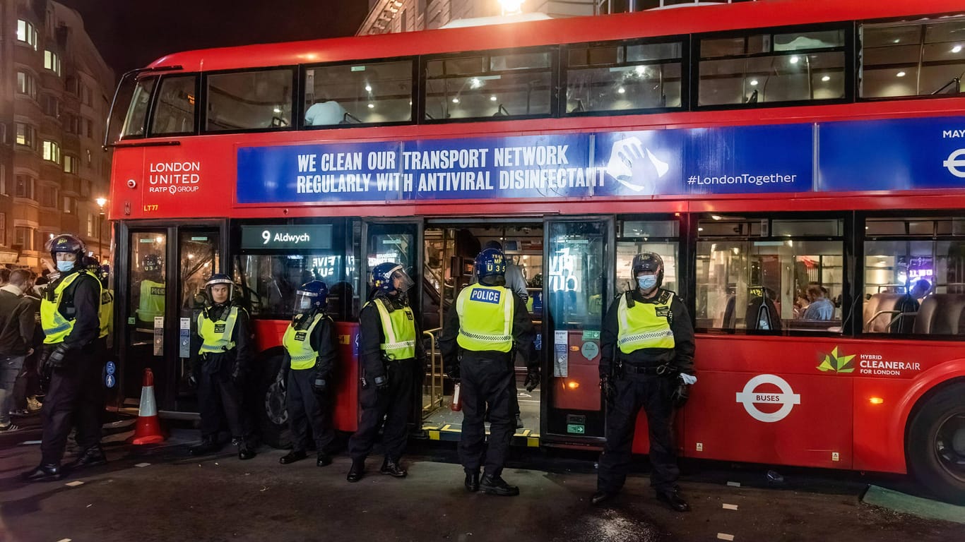 Englische Polizisten bewachen einen Bus, der von Fans zerstört worden ist.