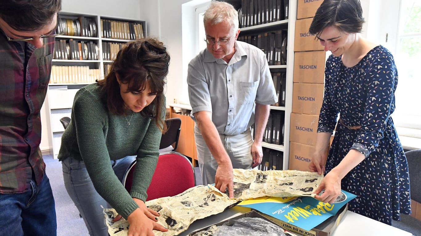 Marcus Plaul (l-r), Wissenschaftlicher Mitarbeiter, Anna-Rosa Haumann, Wissenschaftliche Mitarbeiterin, Patrick Rössler, Professor für Kommunikationswissenschaft und Kathleen Kröger, Studentin der Geschichtswissenschaft, betrachten an der Universität Erfurt eine Sammlung mit Filmwochenschauen.