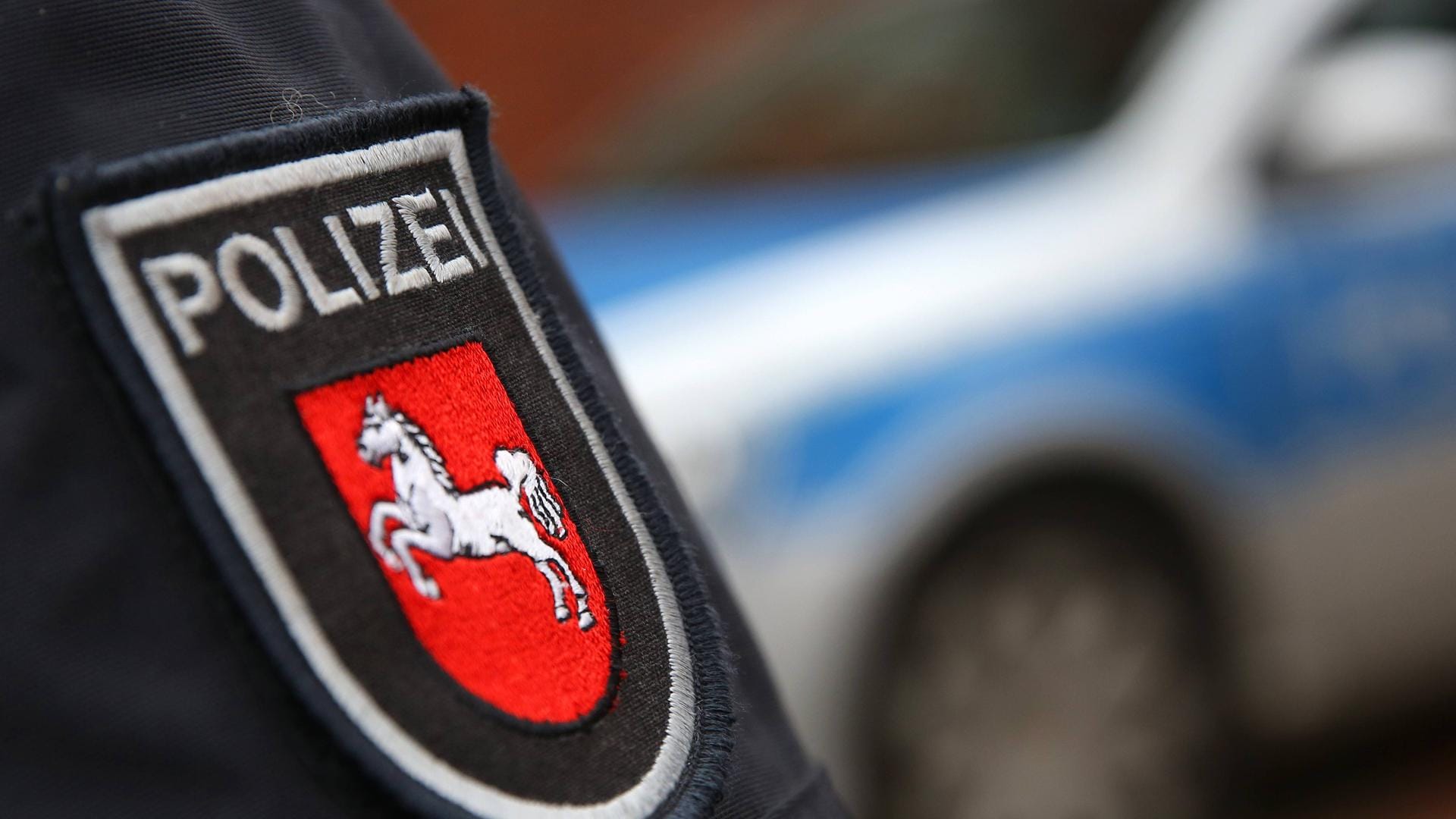 Ein Polizeiwappen auf dem Arm eines Polizisten: Ein Mann war gegen parkende Autos gefahren und hat so einen hohen Sachschaden zu verantworten.