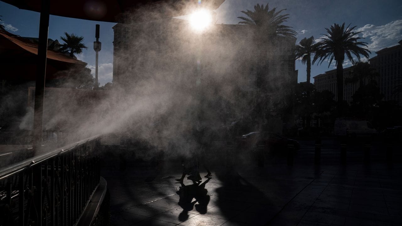 Menschen gehen in Las Vegas an Nebelmaschinen vorbei, die zur Abkühlung entlang der Casino-Meile eingesetzt werden.