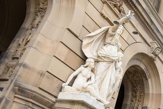 Eine Statue der Justitia hält eine Waagschale