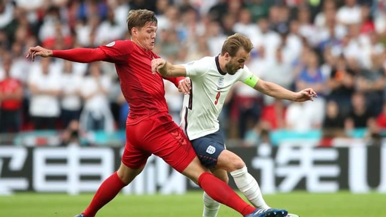 Dänemarks Jannik Vestergaard (l) und Englands Harry Kane kämpfen um den Ball - im Hintergrund eine chinesische Bandenwerbung.