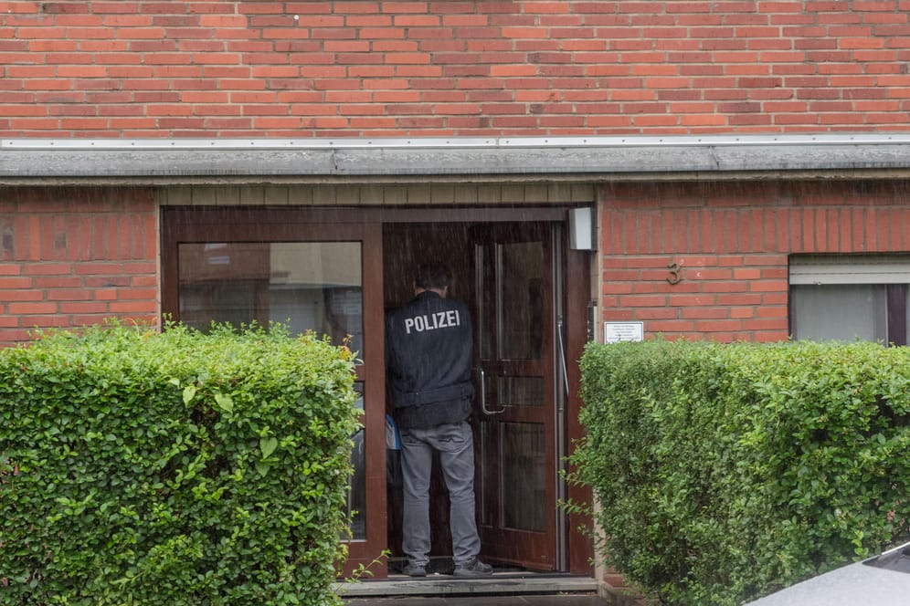 Ein Polizist steht am Eingang eines Hauses in Köln-Bilderstöckchen, in dem am frühen Morgen eine Wohnung durchsucht wurde: Unter den Verdächtigen sollen Mitglieder der Hells Angels sein.