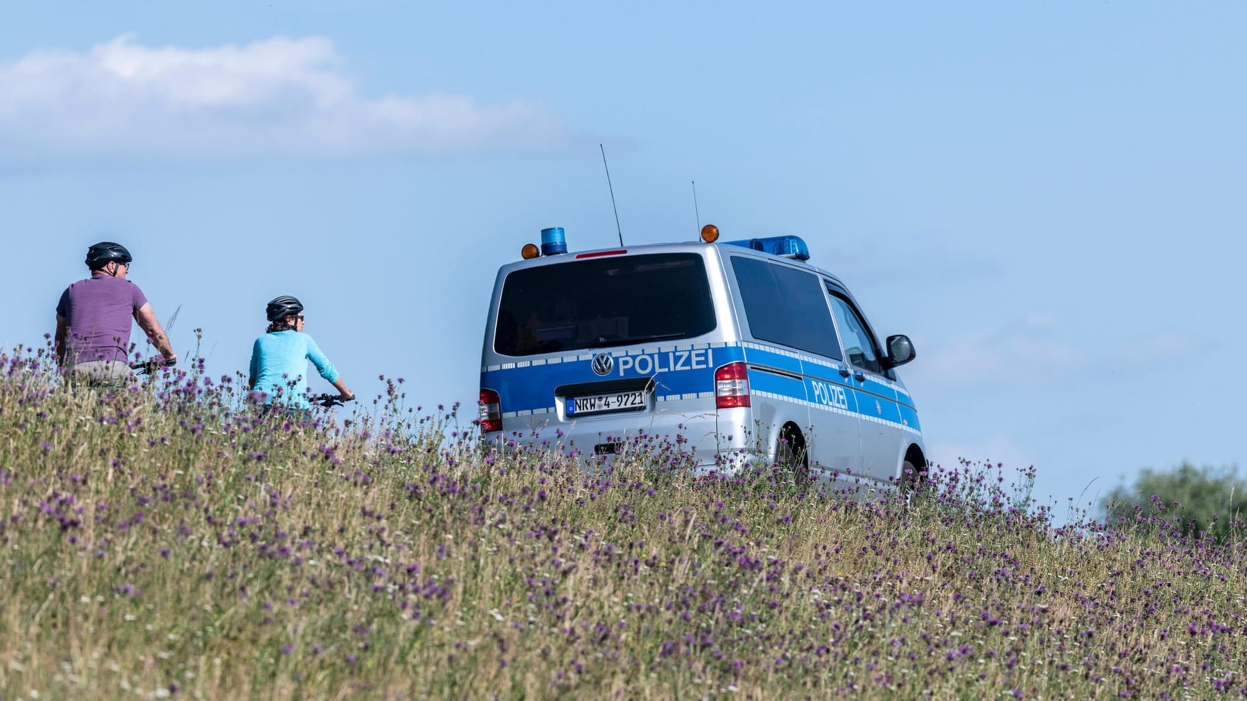 Polizeiwagen neben Fahrradfahrern in der Rheinaue (Symbolbild): Nach einer Unfallflucht durch einen Radfahrer nahe Bonn sucht die Polizei den Unbekannten. Polizeiwagen neben Fahrradfahrern in der Rheinaue (Symbolbild): Nach einer Unfallflucht durch einen Radfahrer nahe Bonn sucht die Polizei den Unbekannten.