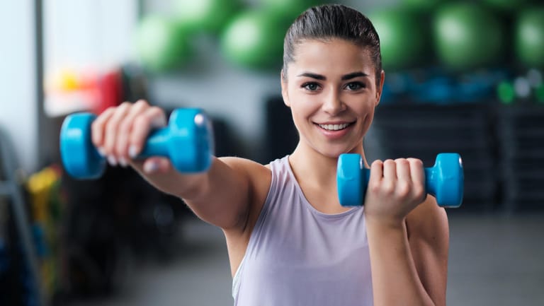 Eine Frau mit Kurzhanteln im Fitnessstudio. Wer trainiert ist, baut nach einer Sportpause schneller wieder Muskeln auf als Ungeübte.