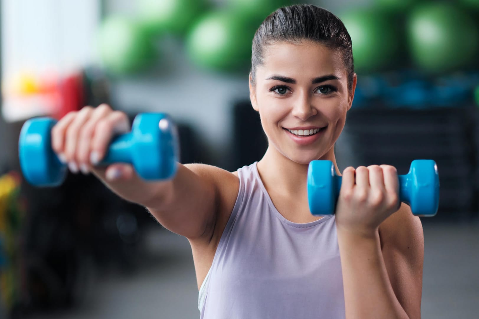 Eine Frau mit Kurzhanteln im Fitnessstudio. Wer trainiert ist, baut nach einer Sportpause schneller wieder Muskeln auf als Ungeübte.