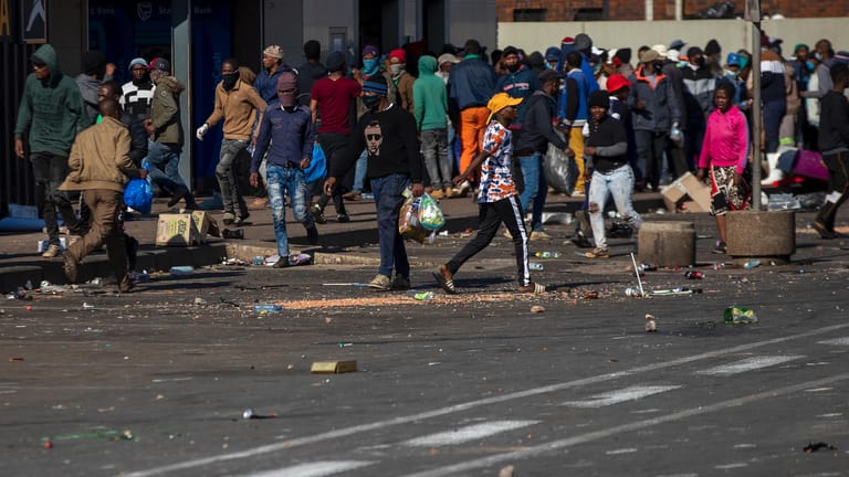 Plünderer tragen Tüten aus einem Einkaufszentrum in Johannesburg: Die Polizei ist den Plünderern aufgrund ihrer Anzahl unterlegen.