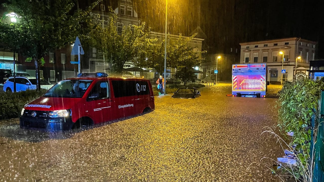 Feuerwehrfahrzeuge und ein PKW stehen auf einer überfluteten Straße: Hunderte Notrufe waren in der Nacht bei der Feuerwehr eingegangen.