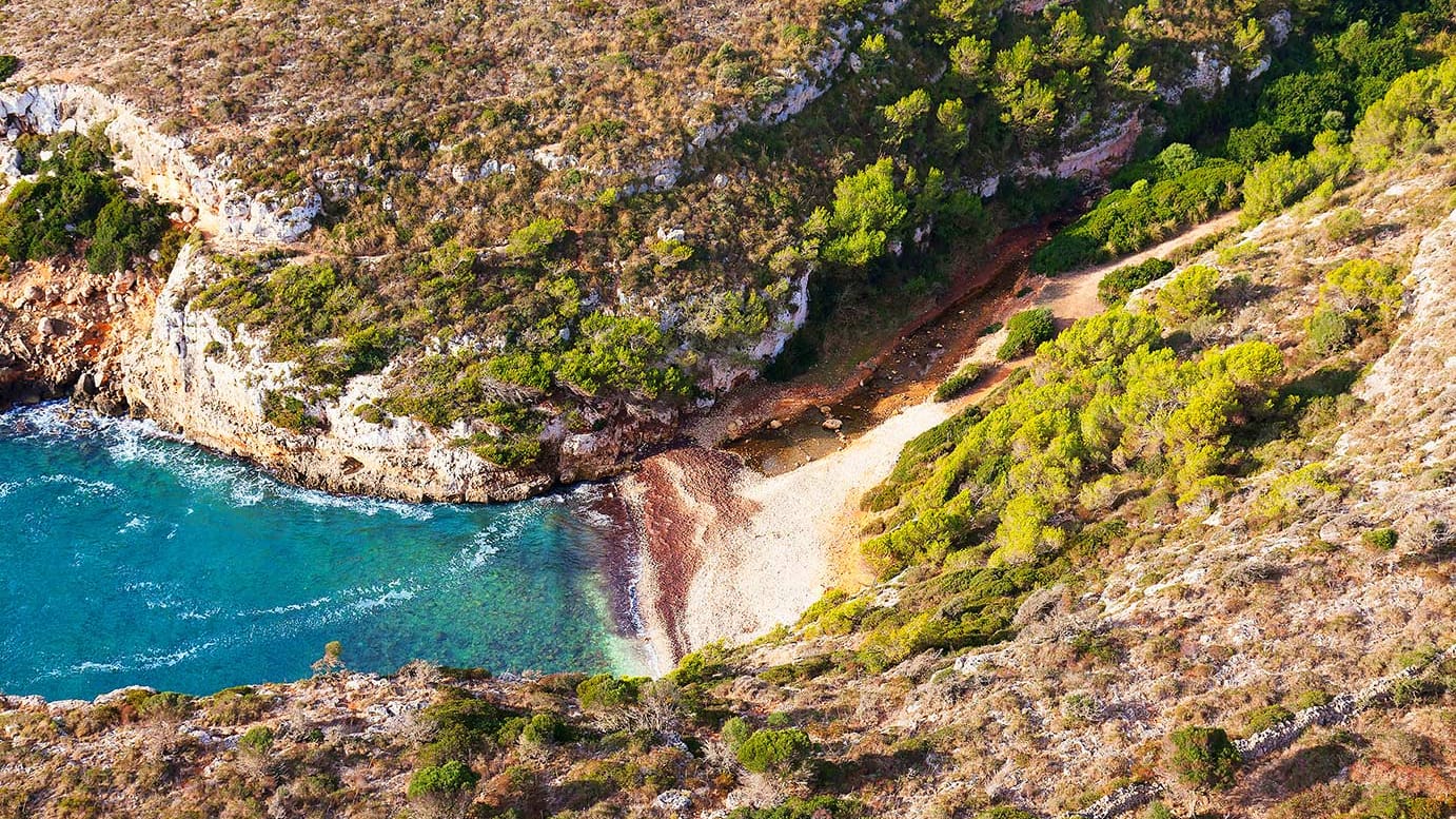 Cala Bota: Die Bucht bietet einen kleinen Strand aus Kies und weißen Kieselsteinen.