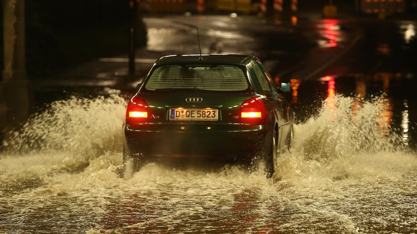 Hochwasser in Düsseldorf: Ein PKW fährt durch eine nach Starkregen überflutete Bahnunterführung.