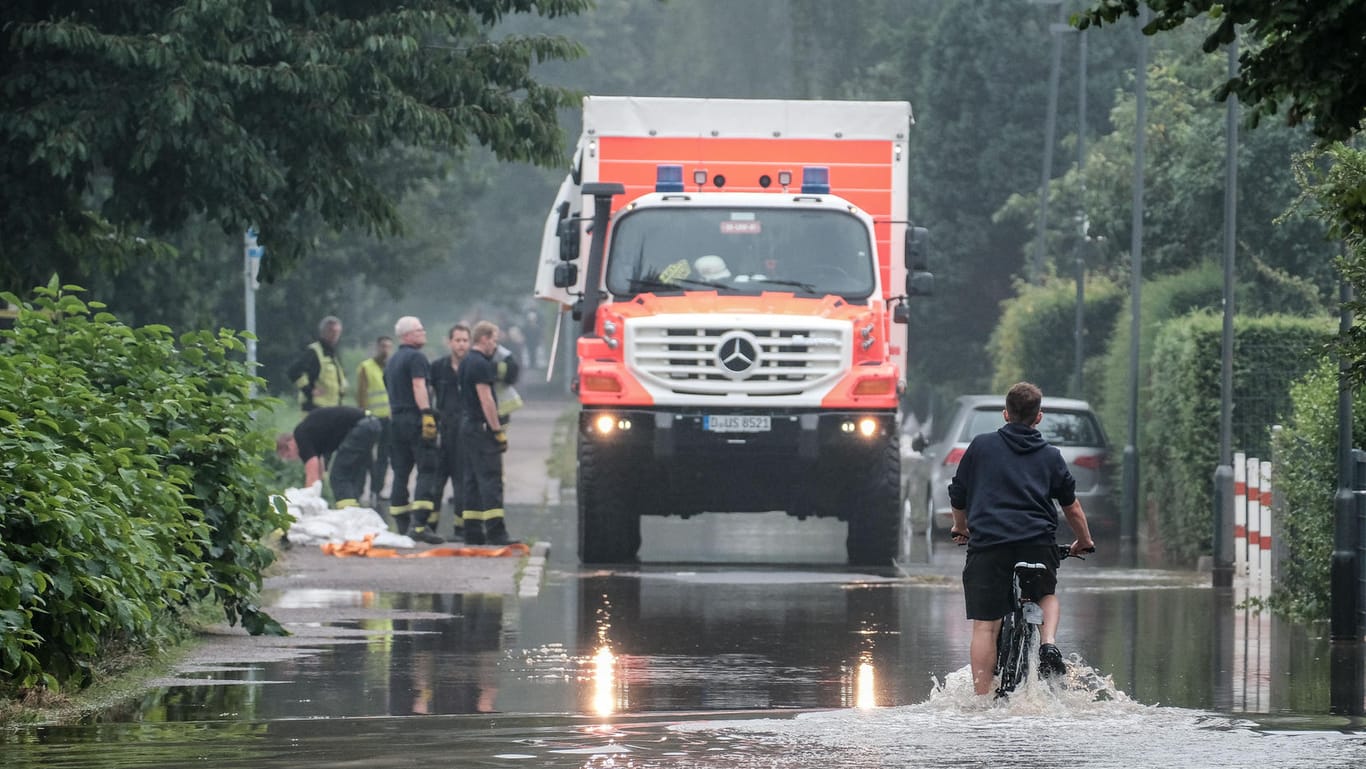 Ein Fahrradfahrer fährt durch eine überflutete Straße in der Ostparksiedlung: Die Anwohner müssen wegen des Hochwassers ihre Häuser verlassen.