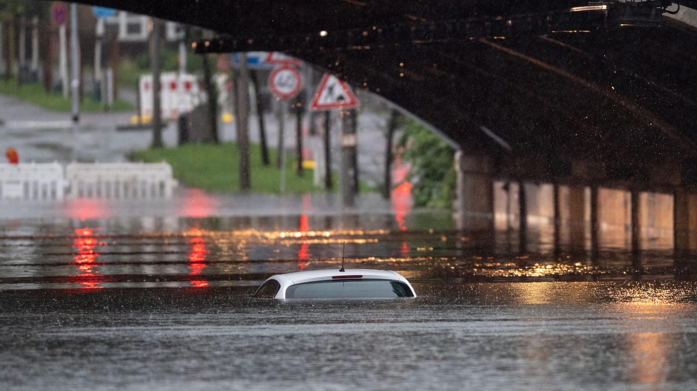 Eine überflutete Bahnunterführung in Köln: Nur noch das Dach dieses Autos ist zu sehen, so hoch steht das Wasser.