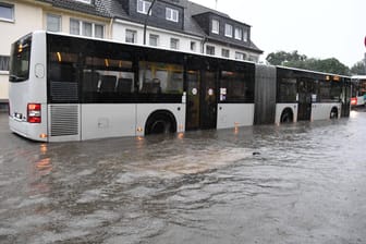 Ein Bus der KVB fährt auf einer überfluteten Straße in Müngersdorf: In der gesamten Stadt und Umgebung kommt es zu Beeinträchtigungen im Verkehr.