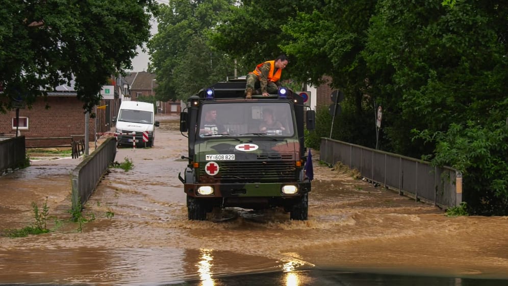 Erfstadt, Nordrhein-Westfalen: Ein Fahrzeug der Bundeswehr fährt durch eine überflutete Straße. Das Regen-Unwetter in Nordrhein-Westfalen hat auf zahlreichen Autobahnen für überflutete Fahrbahnen gesorgt.