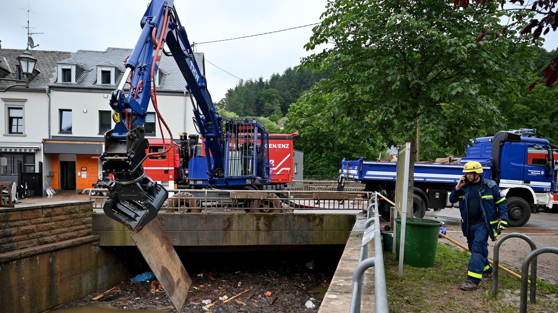 Ein Bagger des THW ist mit Aufräumarbeiten an einem Bachbett beschäftigt (Symbolbild): Handelsunternehmen verteilen Werkzeug und Lebensmittel an Helfer.