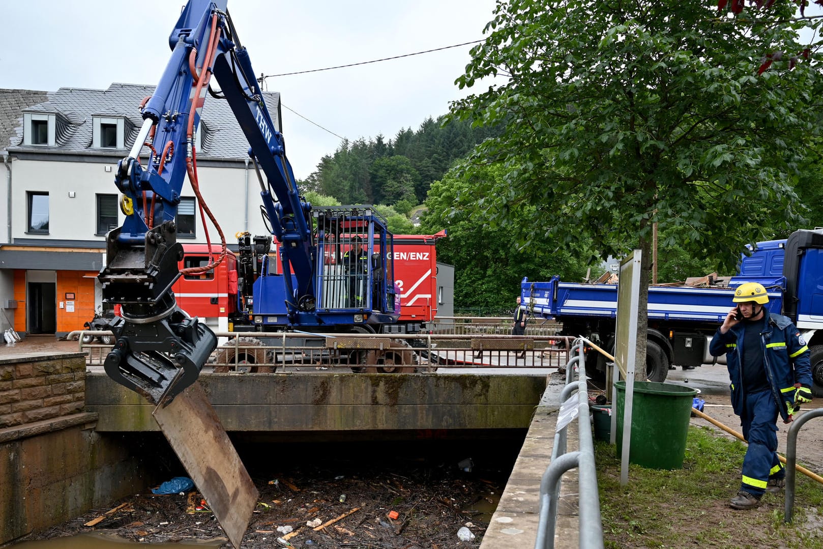 Ein Bagger des THW ist mit Aufräumarbeiten an einem Bachbett beschäftigt (Symbolbild): Handelsunternehmen verteilen Werkzeug und Lebensmittel an Helfer. Ein Bagger des THW ist mit Aufräumarbeiten an einem Bachbett beschäftigt (Symbolbild): Handelsunternehmen verteilen Werkzeug und Lebensmittel an Helfer.