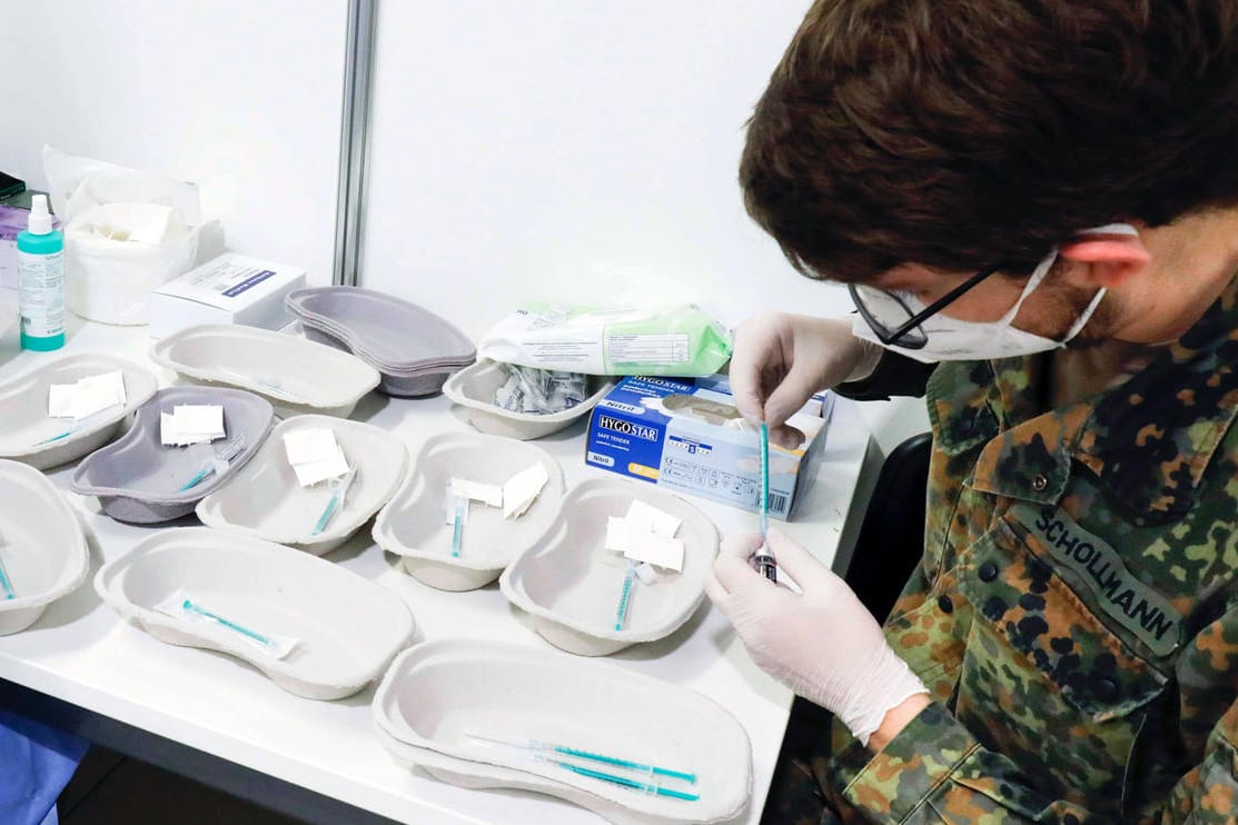 Ein Bundeswehrsoldat zieht in einem Impfzentrum eine Spritze auf (Archivbild). Die Wehrbeauftragte fordert eine Impfpflicht für die gesamten Streitkräfte.