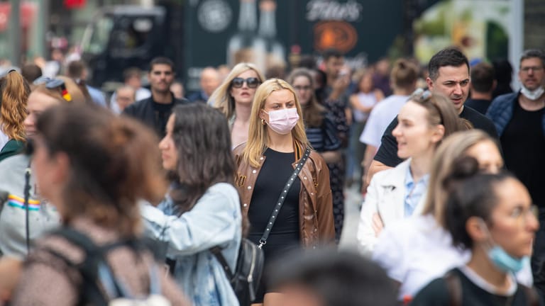 London: Eine Frau trägt in einer Gruppe von Fußgängern einen Mund-Nasen-Schutz.