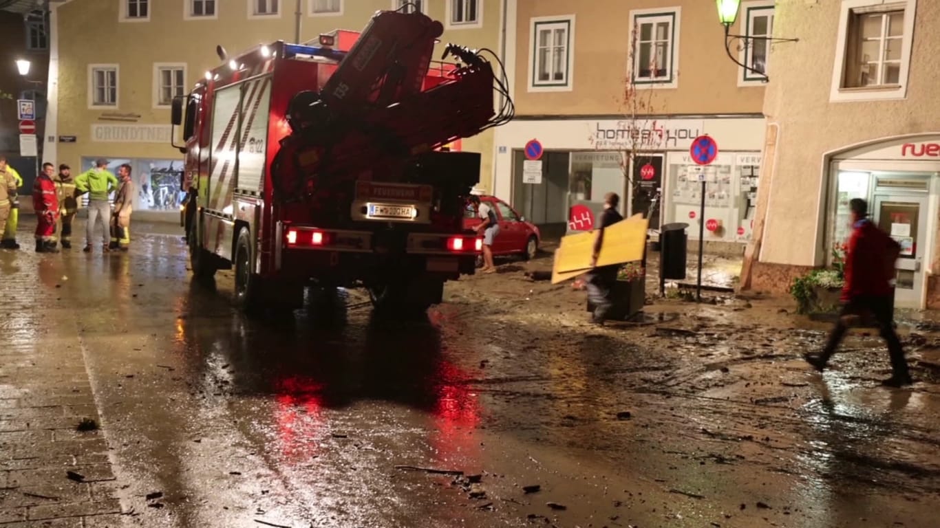 Nächtliche Aufräumarbeiten auf einer vom Hochwasser betroffenen Straße. Nach sintflutartigen Regenfällen sind in Österreich Teile der Altstadt von Hallein überflutet worden