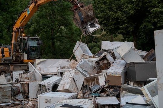 Ein Bagger entsorgt in Kordel (Rheinland-Pfalz) Elektrogeräte, die durch das Hochwasser beschädigt wurden.