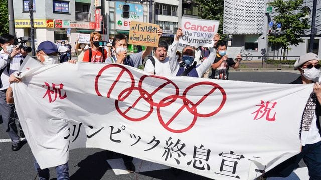 Demonstranten marschieren mit einem Banner und Plakaten bei einem Protest gegen die Olympischen und Paralympischen Sommerspiele. Demonstranten marschieren mit einem Banner und Plakaten bei einem Protest gegen die Olympischen und Paralympischen Sommerspiele.