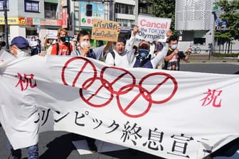 Demonstranten marschieren mit einem Banner und Plakaten bei einem Protest gegen die Olympischen und Paralympischen Sommerspiele.