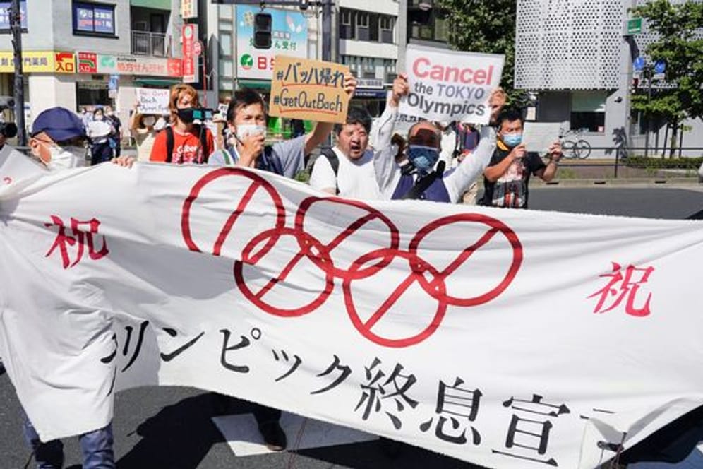 Demonstranten marschieren mit einem Banner und Plakaten bei einem Protest gegen die Olympischen und Paralympischen Sommerspiele.