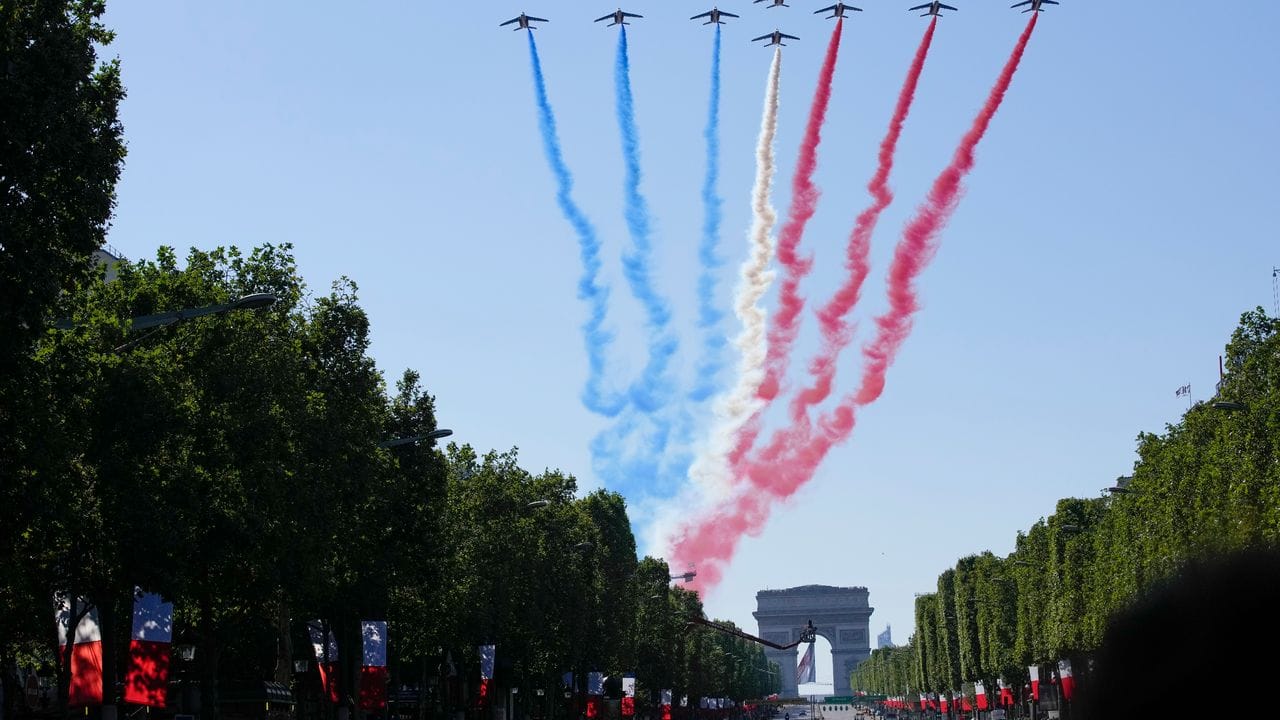 Jets der Patrouille de France fliegen über den Arc de Triumph und die Champs Elysees.