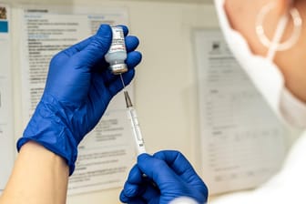 Eine Person zieht eine Spritze mit Impfstoff gegen das Coronavirus auf (Symbolbild): Hunderte Bremer müssen möglicherweise ein drittes Mal geimpft werden.