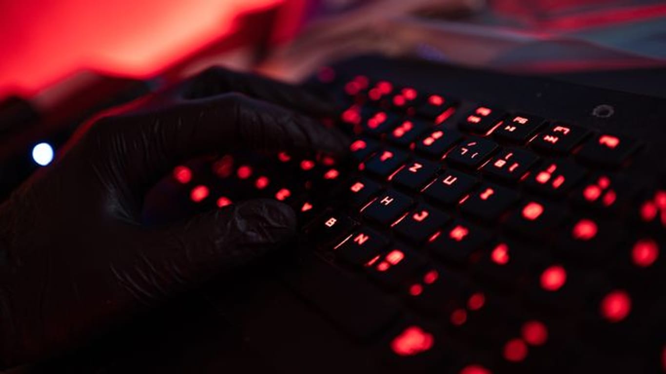 Ein Mann trägt Handschuhe und tippt auf einer Tastatur.
