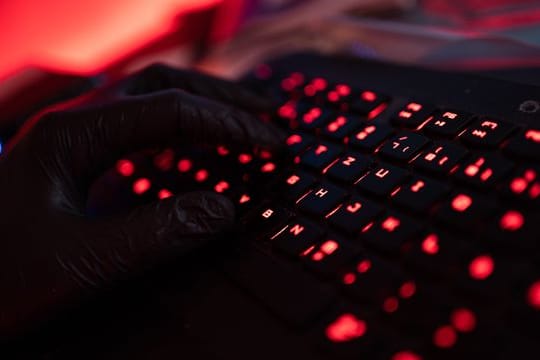 Ein Mann trägt Handschuhe und tippt auf einer Tastatur.