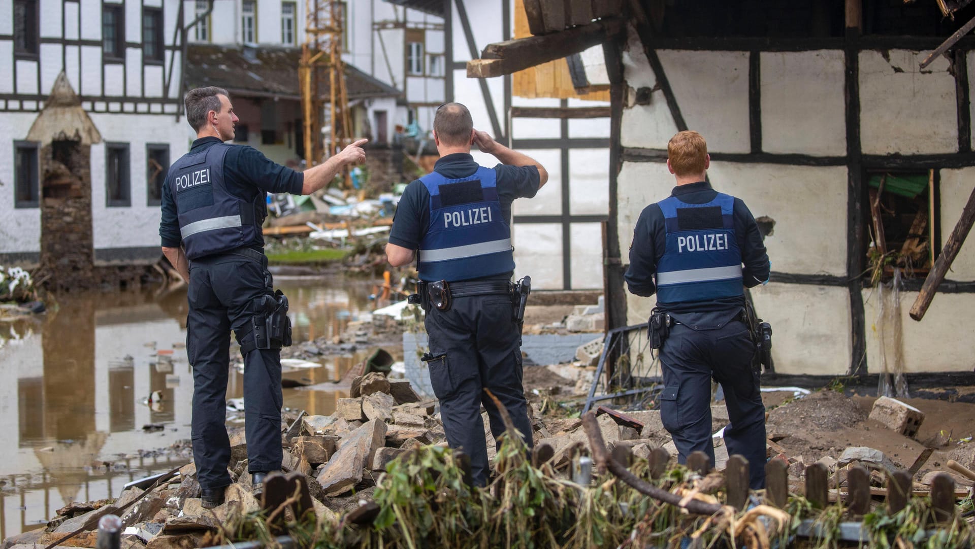 Polizisten stehen vor Verwüstungen (Symbolbild): Offenbar nutzen Kriminelle die Unwetterkatastrophe aus. Polizisten stehen vor Verwüstungen (Symbolbild): Offenbar nutzen Kriminelle die Unwetterkatastrophe aus.