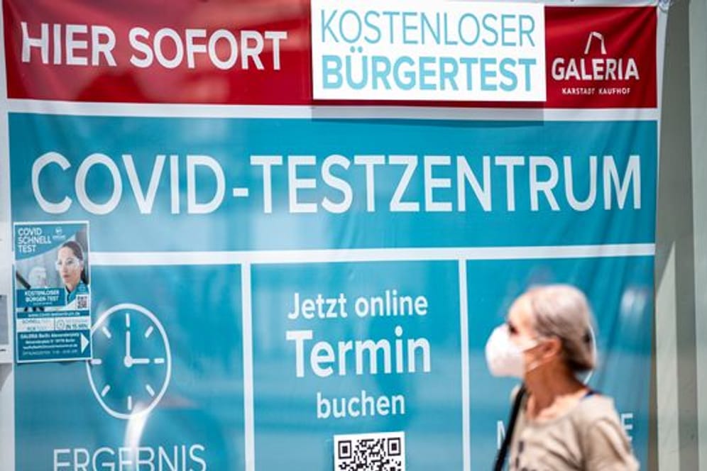 Eine Frau mit Maske läuft an einem Corona-Testzentrum am Berliner Alexanderplatz vorbei.