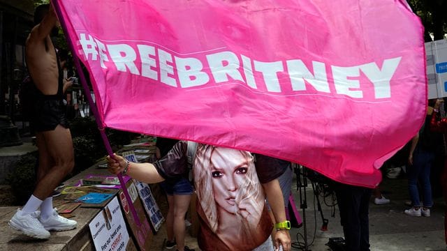 Ein Britney Spears-Anhänger schwenkt eine "Free Britney"-Fahne im Rahmen einer Gerichtsanhörung zur Vormundschaft der Popsängerin. Ein Britney Spears-Anhänger schwenkt eine "Free Britney"-Fahne im Rahmen einer Gerichtsanhörung zur Vormundschaft der Popsängerin.