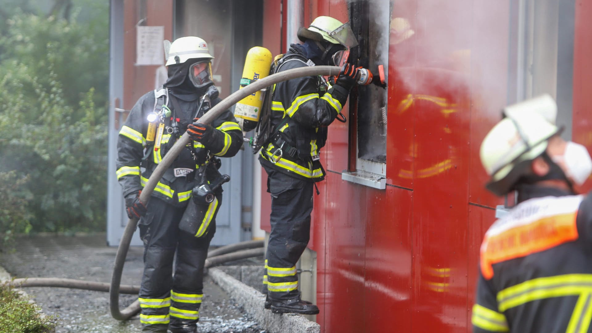 Feuerwehrleute löschen einen Brand in einer Flüchtlingsunterkunft: Noch ist die Ursache für das Feuer unklar. Feuerwehrleute löschen einen Brand in einer Flüchtlingsunterkunft: Noch ist die Ursache für das Feuer unklar.