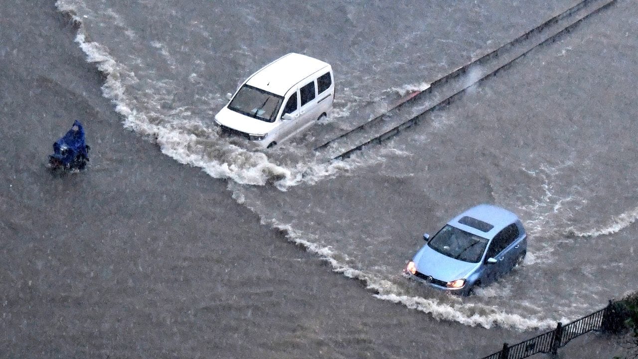 Fahrzeuge fahren in Zhengzhou in der zentralchinesischen Provinz Henan durch die Fluten.
