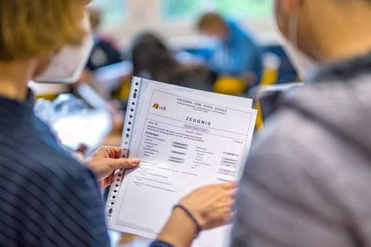 Die Klassenlehrerin übergibt das Zeugnis eines Schülers