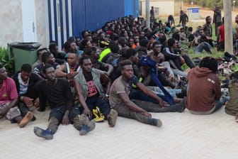 In der spanischen Nordafrika-Exklave Melilla: Eine Gruppe von Menschen sitzt vor einem Aufnahmezentrum für Migranten.