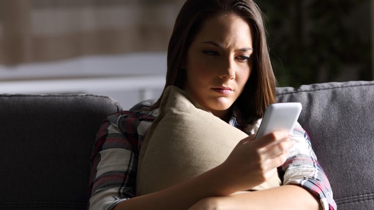 Eine Frau blickt skeptisch auf ihr Smartphone (Symbolbild): Viele Webseiten waren wegen einer Störung am Donnerstag zeitweise nicht erreichbar.