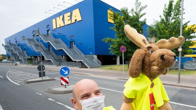 Ein Mann steht mit einem Stoffelch vor der Ikea-Filiale