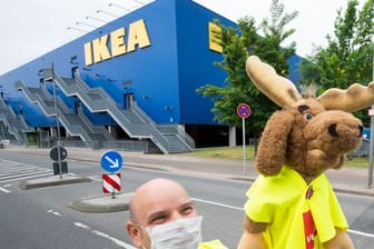 Ein Mann steht mit einem Stoffelch vor der Ikea-Filiale