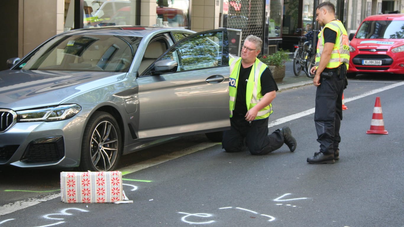 Polizisten inspizieren den Unfallwagen: Der BMW-Fahrer hatte beim Öffnen der Tür offenbar nicht auf den Verkehr geachtet.
