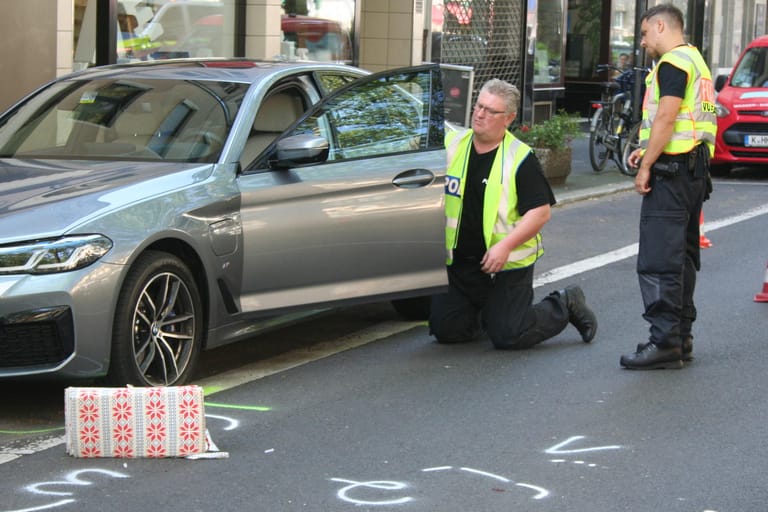 Polizisten inspizieren den Unfallwagen: Der BMW-Fahrer hatte beim Öffnen der Tür offenbar nicht auf den Verkehr geachtet.