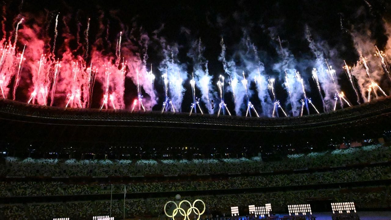 Die Olympischen Ringe leuchten unter buntem Feuerwerk.