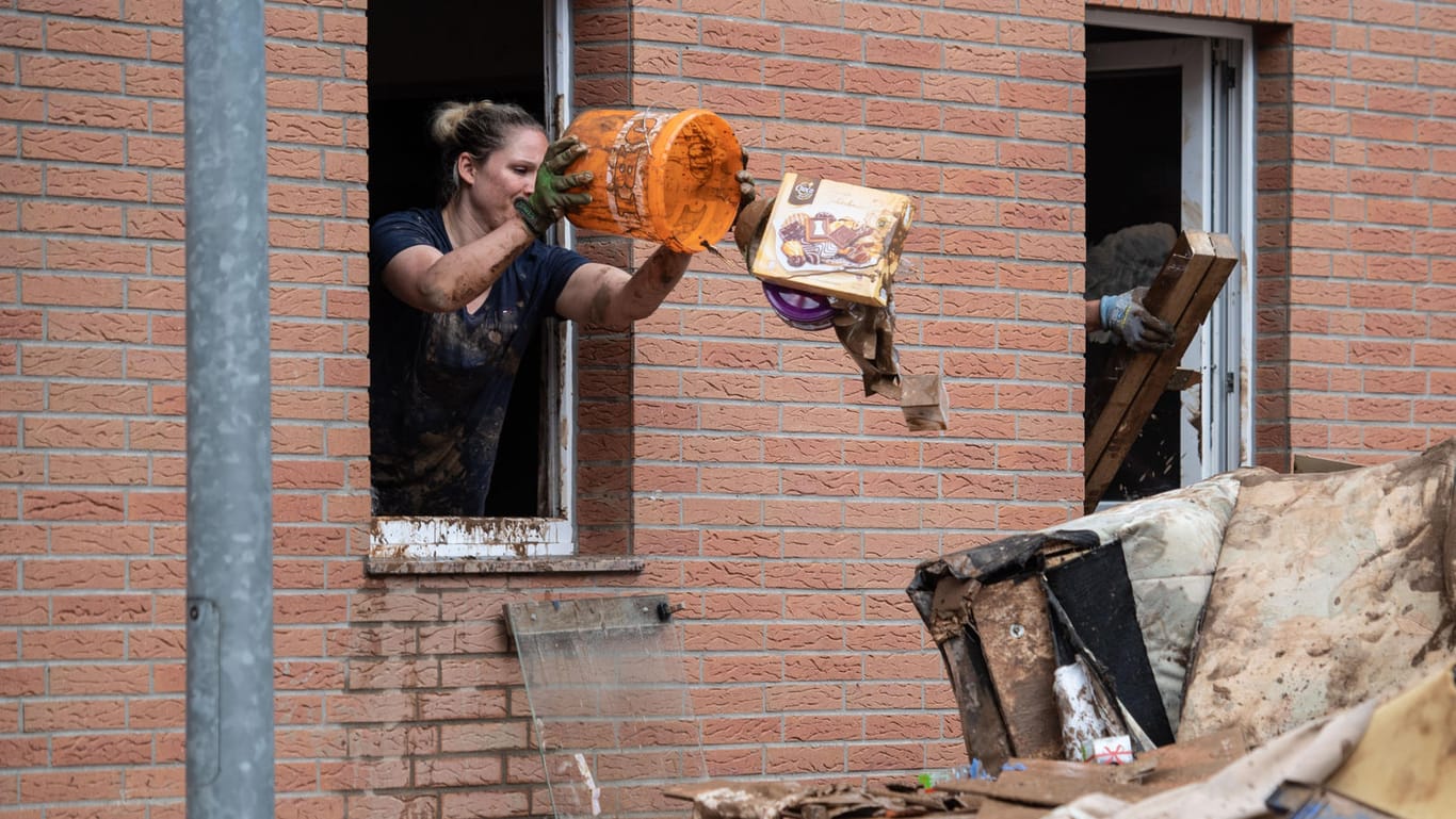 Eine Frau wirft Unrat aus dem Haus: Im Katastrophengebiet dürfen einige Anwohner dauerhaft in ihre Häuser zurück.