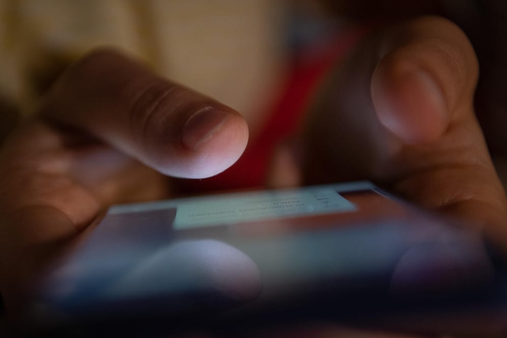 Ein Mann hält sein Smartphone fest: Mit der Software Pegasus sollen weltweit zahlreiche Telefone ausgespäht worden sein. (Symbolfoto)