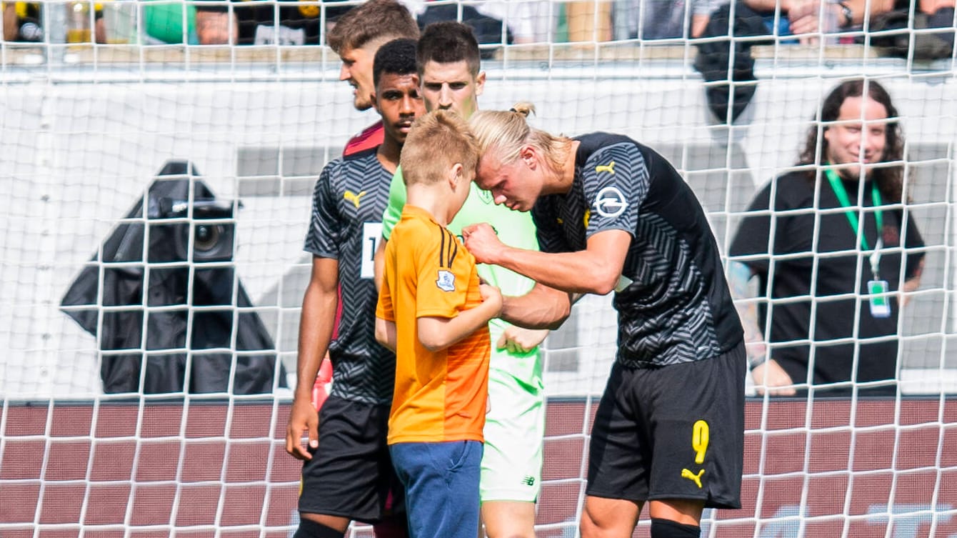 Erling Haaland (re.) unterzeichnet während des Testspiels gegen Bilbao das Shirt eines jungen Fans.