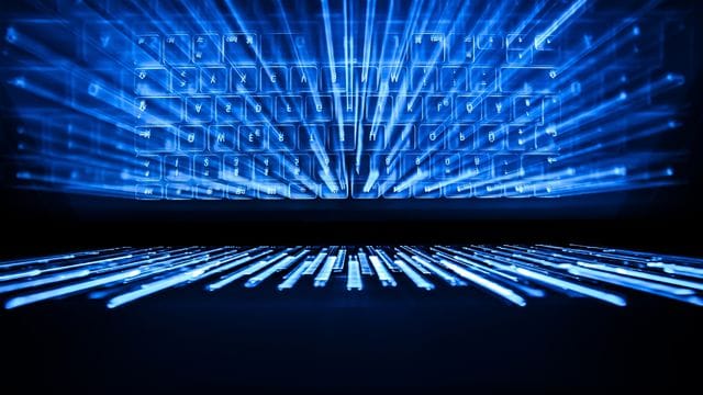Die beleuchtete Tastatur eines Laptops spiegelt sich im Bildschirm. Die beleuchtete Tastatur eines Laptops spiegelt sich im Bildschirm.