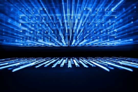 Die beleuchtete Tastatur eines Laptops spiegelt sich im Bildschirm.